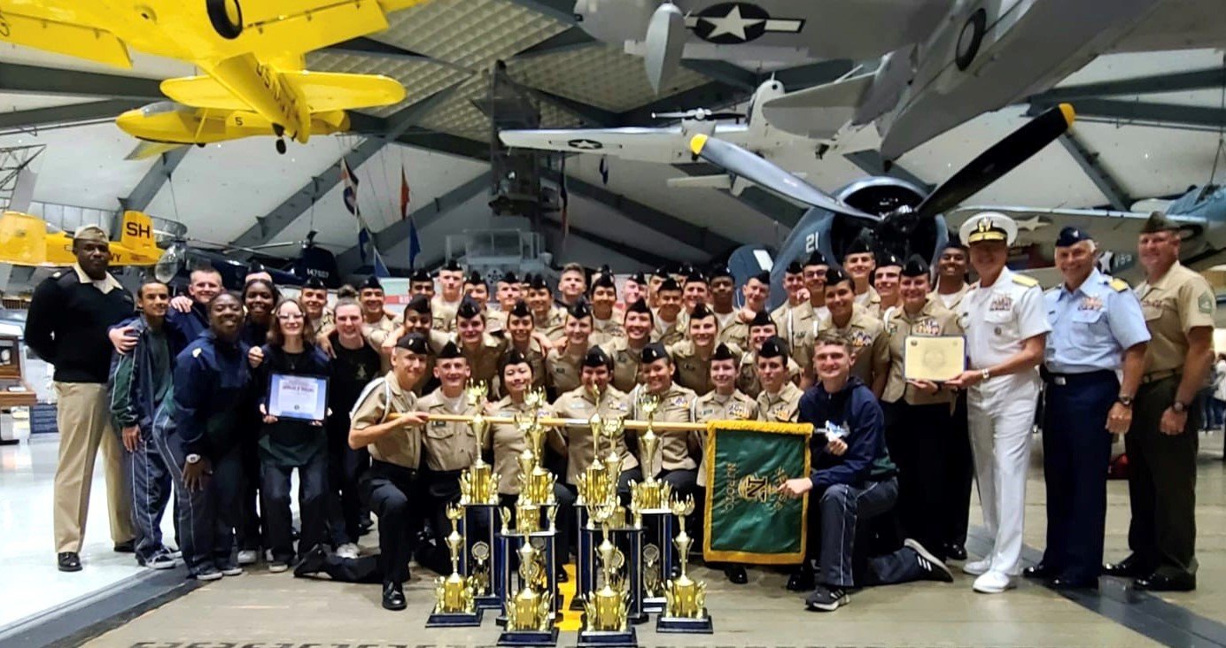 Nease NJROTC’s Drill Team poses with Rear Admiral Peter A. Garvin and their 11 hard-earned trophies at the Navy National Academic, Athletic and Drill Championships.