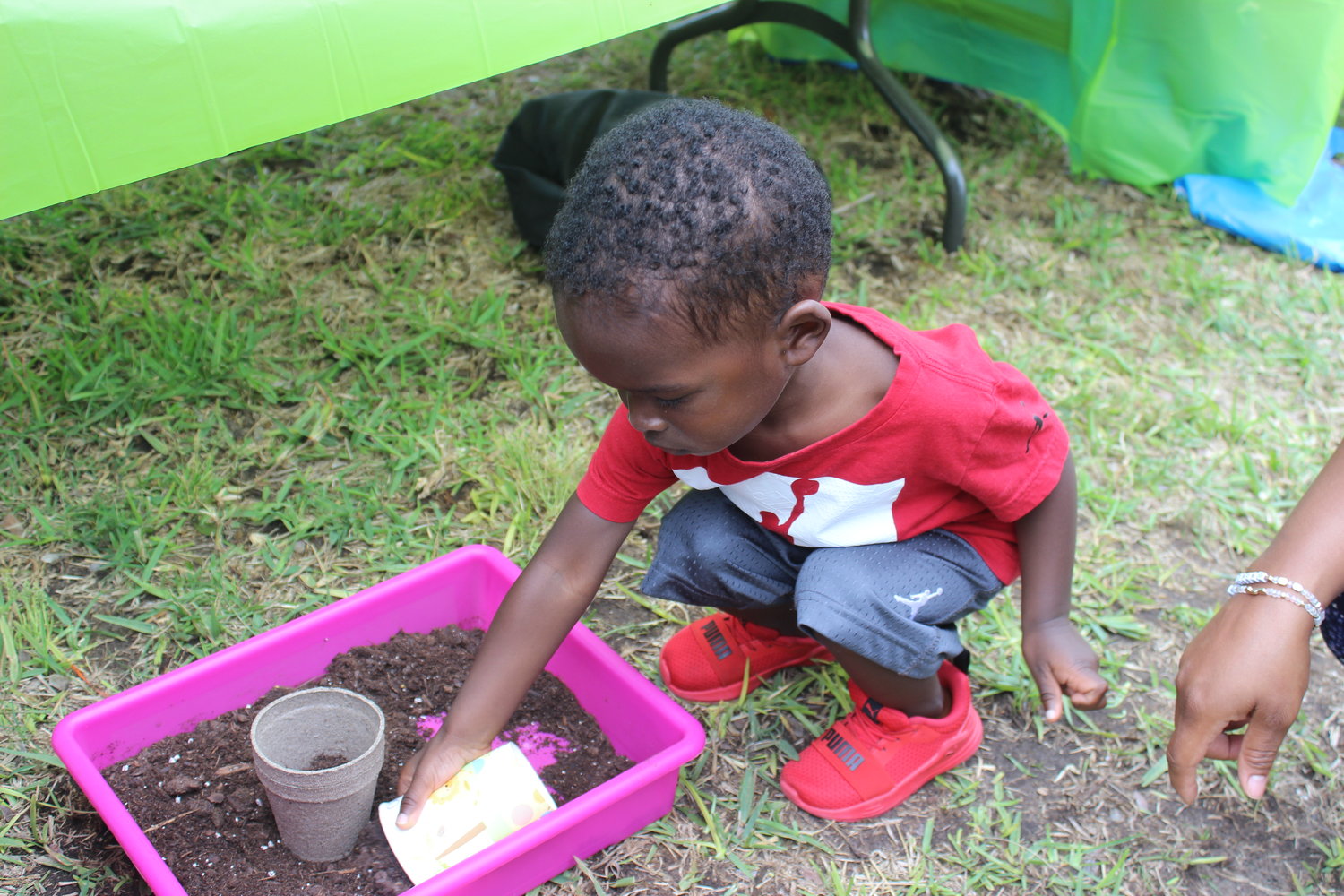 Jeremiah Georges scoops up some soil to plant seeds in a cup.